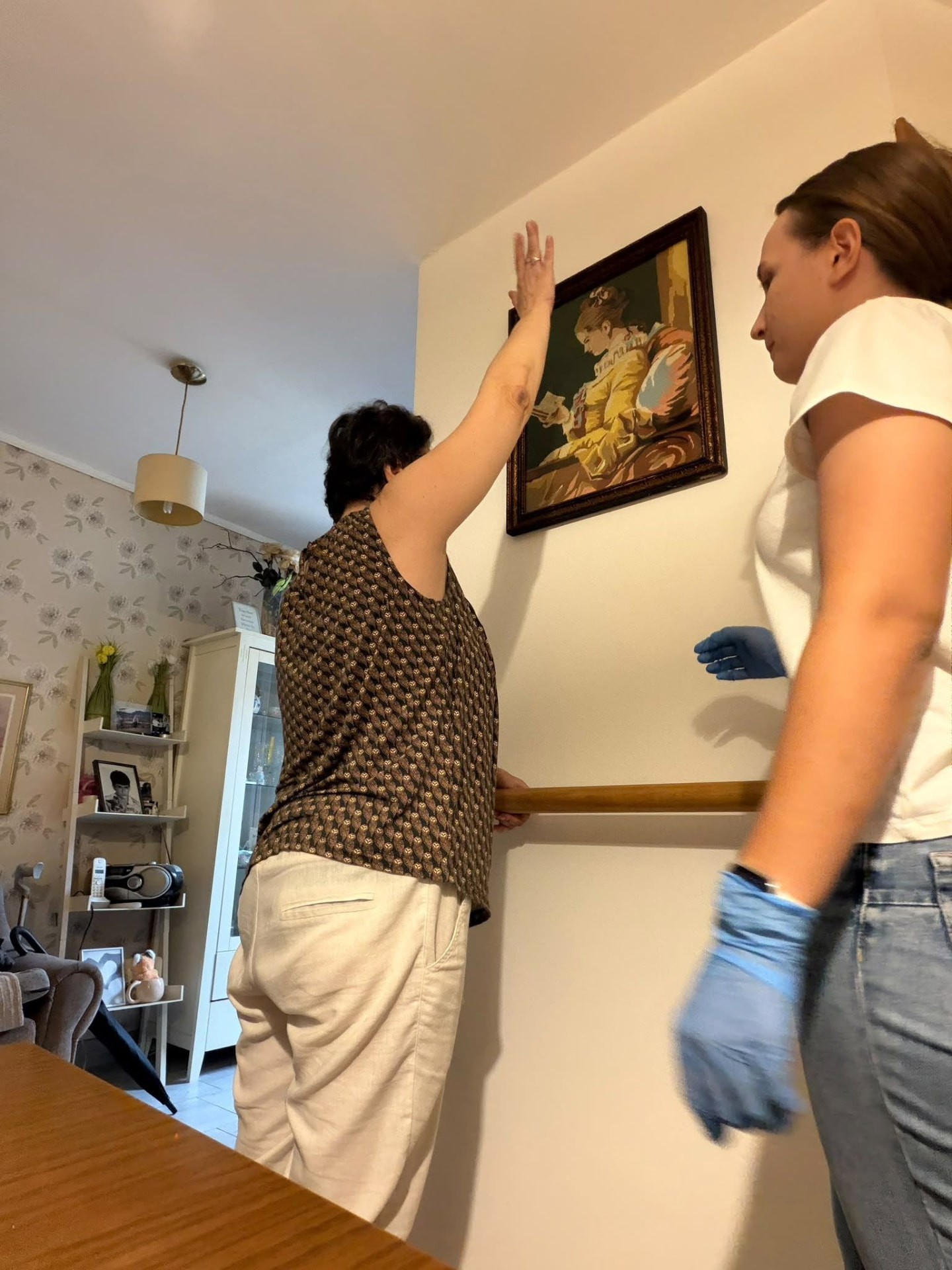 A caregiver supporting a woman during a mobility exercise at home